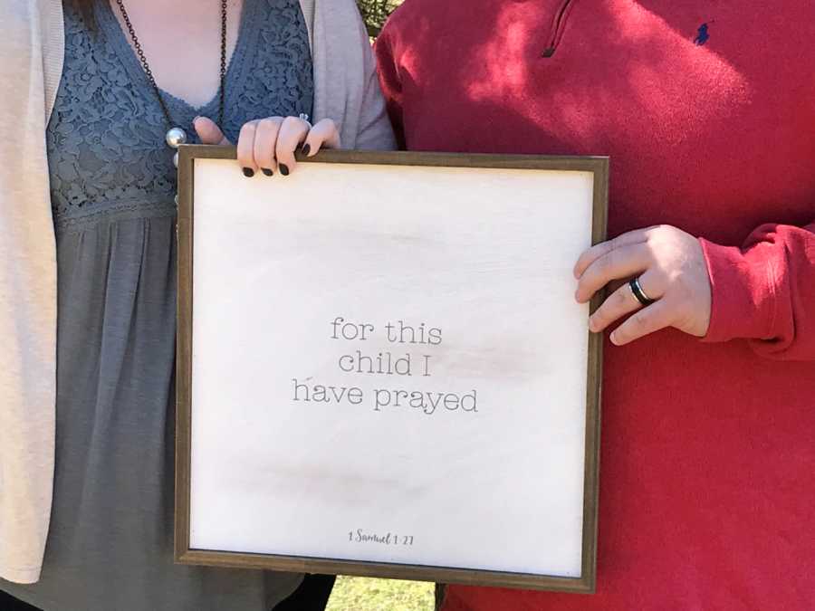 Husband and wife who was infertile hold sign that says, "for this child I have prayed"