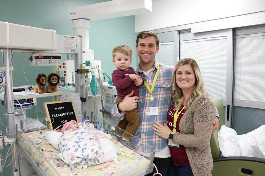 Mother and Father hold firstborn next to sleeping newborn after open heart surgery