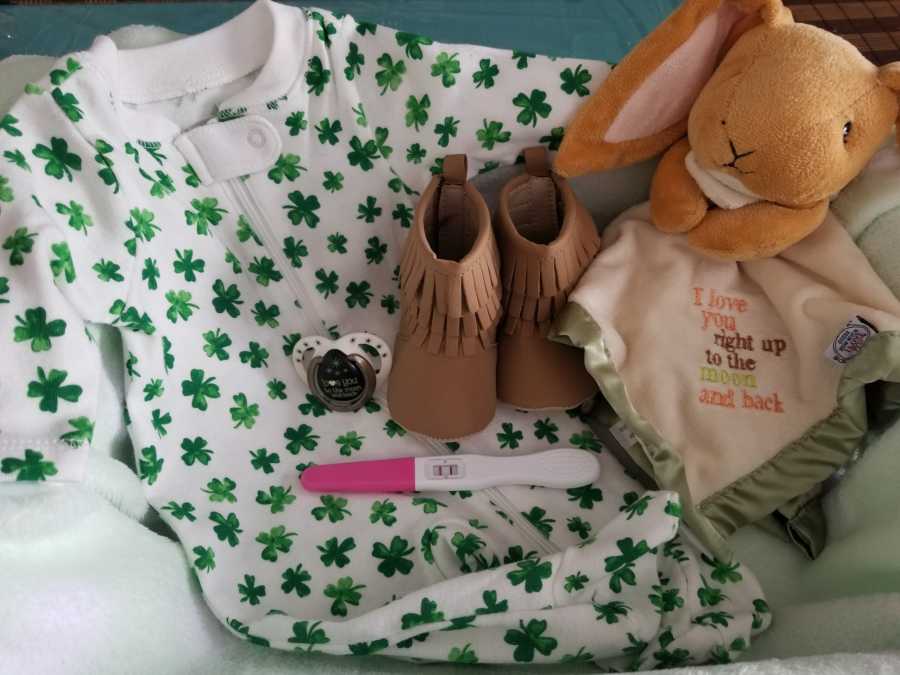 Four-leaf clover onesie, pregnancy test, and other baby memorabilia for baby of woman who struggled with fertility 