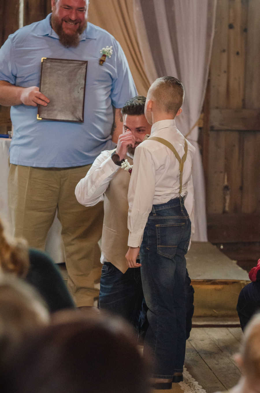 Stepdad kneels in front of stepson crying at his wedding