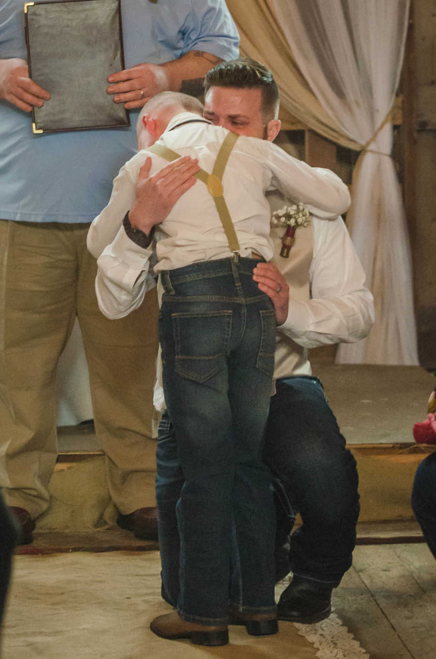 Stepdad kneeling and crying while hugging stepson