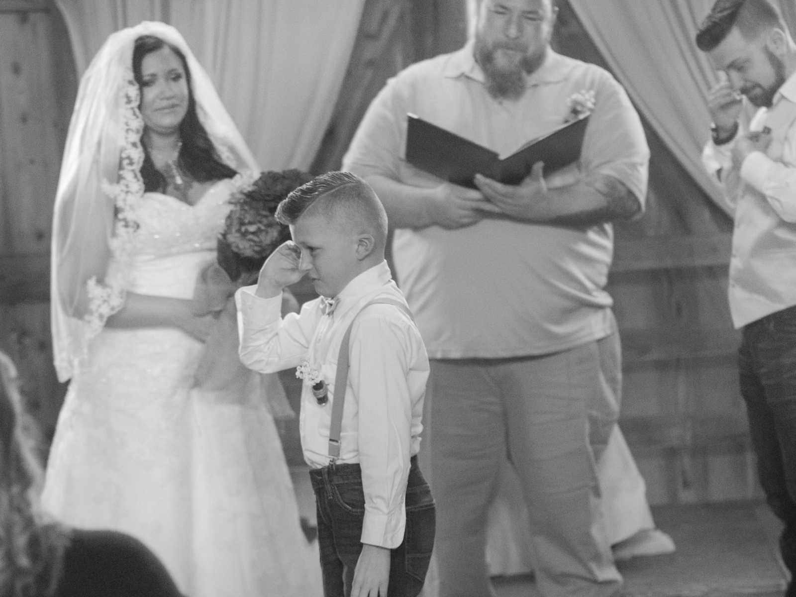 Boy walking away from altar wiping his tears as his mom marries his stepdad