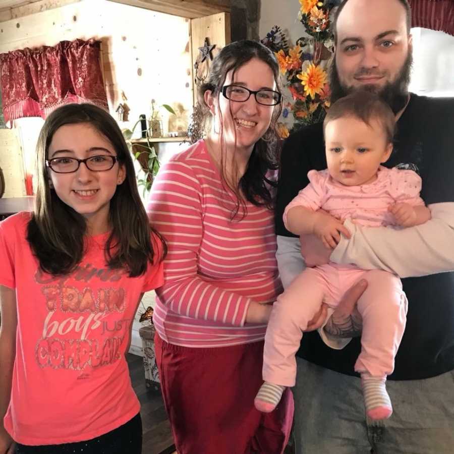 Sober mother and father smile with toddler daughter and mother's first born daughter