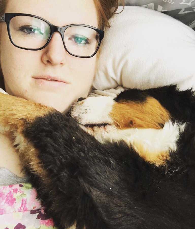 Woman who is scared her mental illness makes her unlovable lies in bed in selfie with dog