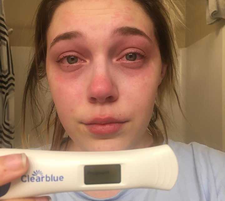 Woman cries in selfie holding up clear blue pregnancy test that says pregnant