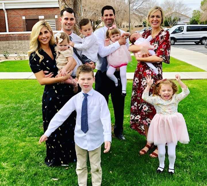 Husband and wife stand holding son next to mother and father of adopted children