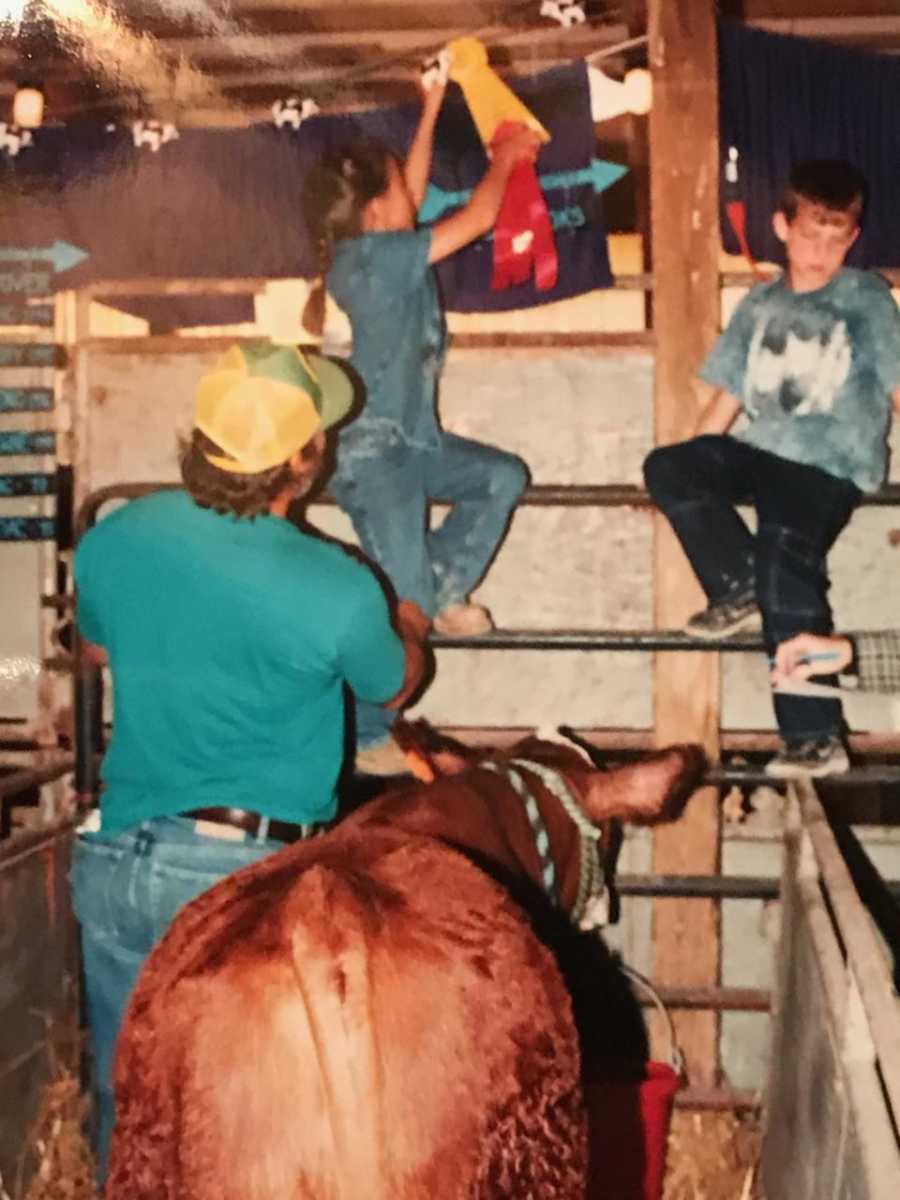 Bride when she was younger putting up a red ribbon at farm with her dad holding her up