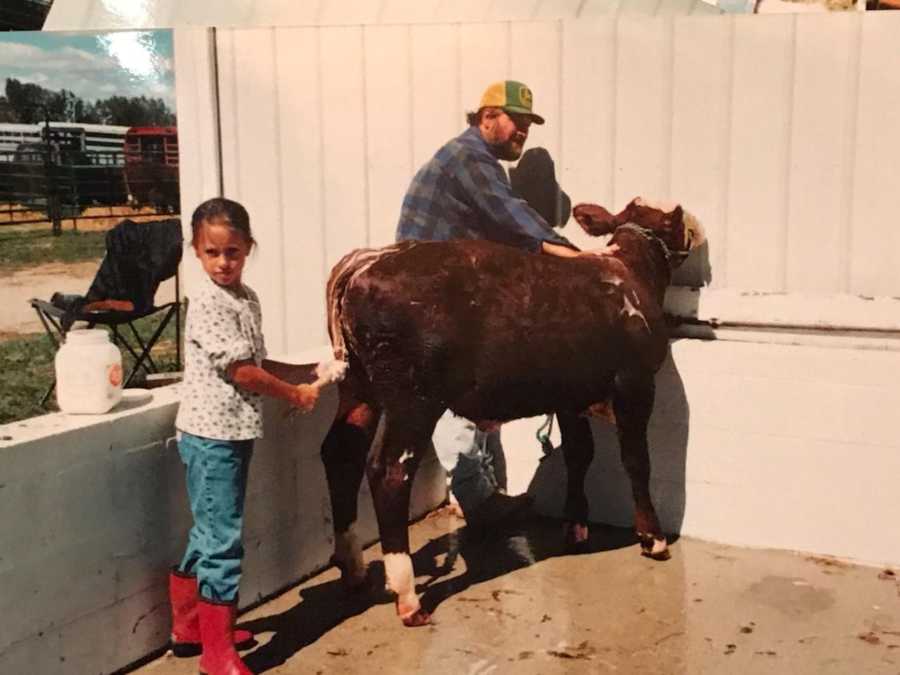 Farmer father and daughter wash down cow