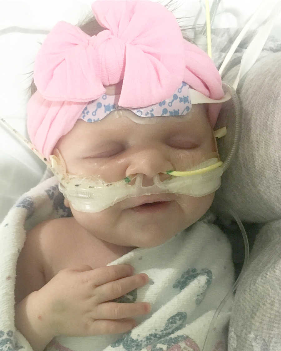 Newborn baby girl with big pink bow on her head and tubes up her nose before she passes away