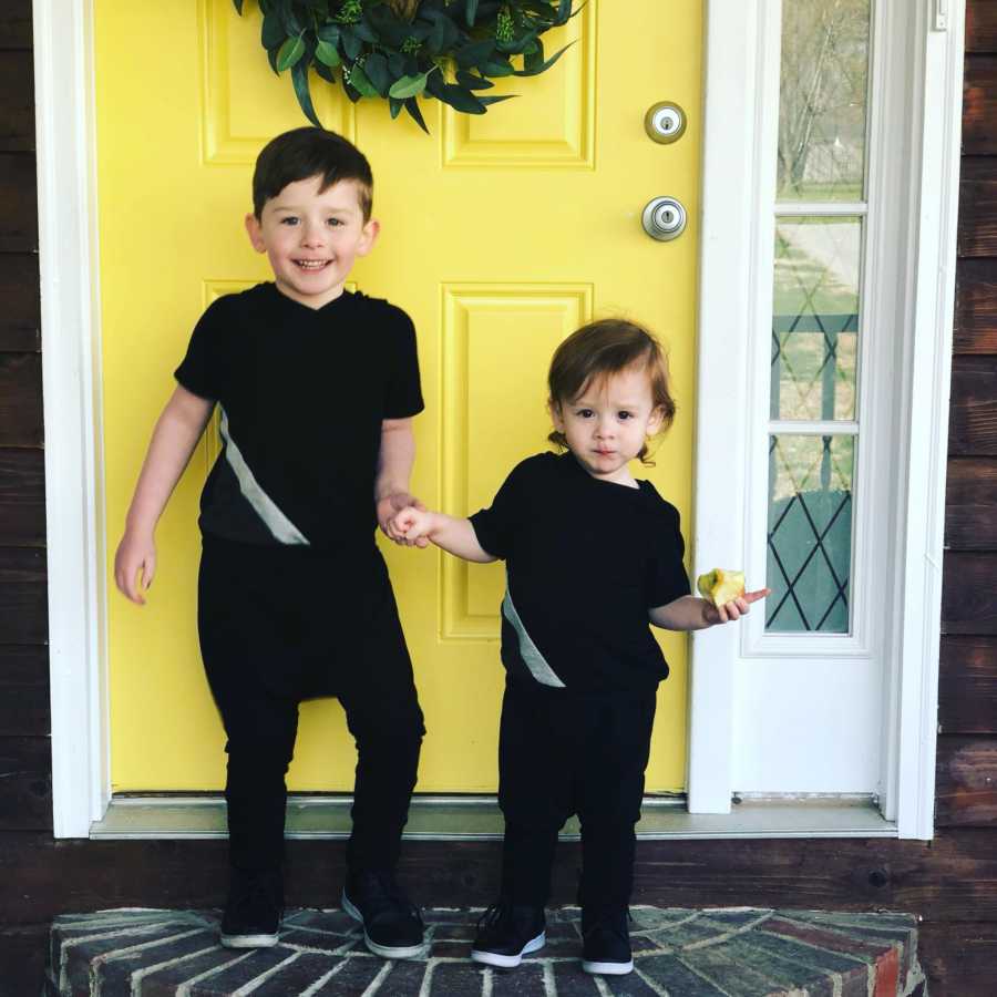 Two sons of woman who cherishes her kids childhood standing in front of yellow front door