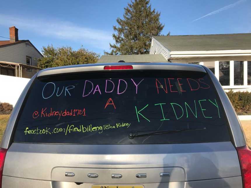Silver dodge van rear windshield with message, "our daddy needs a kidney" on it
