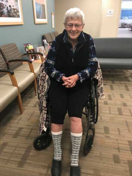 Woman with dementia smiling in wheel chair wearing capris and tall socks with snowflakes on them