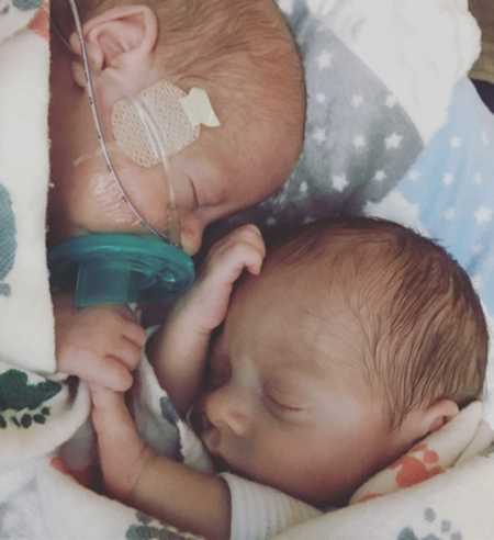 Newborn twins holding hands while sleeping