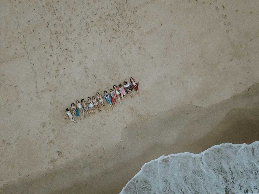 Aerial view of women lying on their back on the beach while breastfeeding