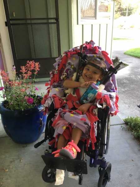 Toddler who was internally decapitated smiling in wheel chair wearing a halo brace
