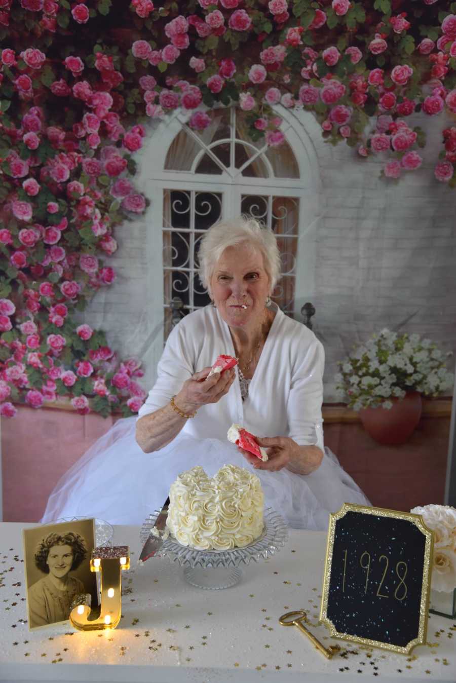 90 year old woman smiles as she eats with two handfuls of cake