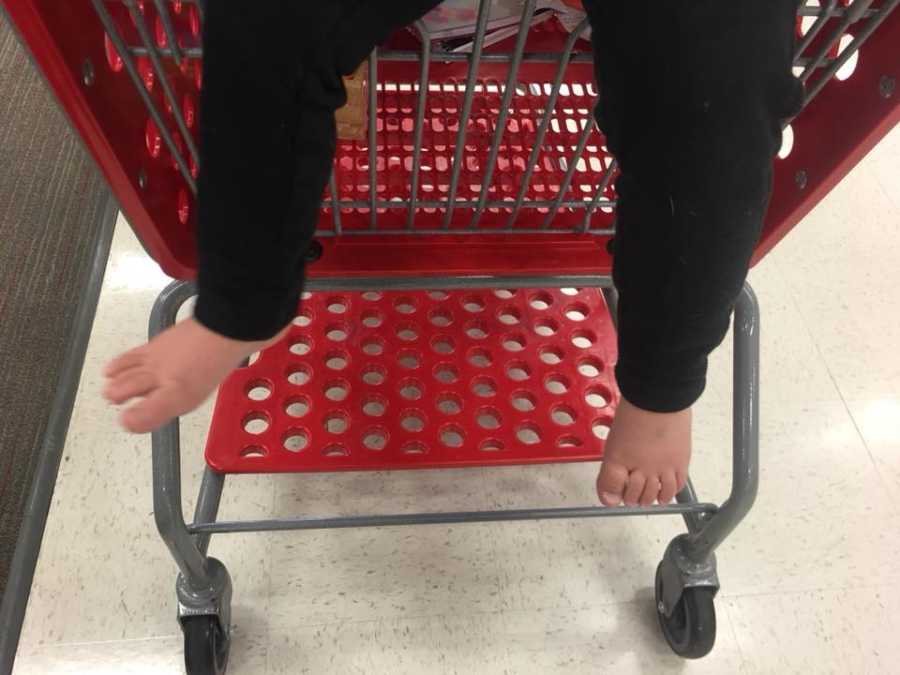 Child sitting in Target shopping cart without shoes on