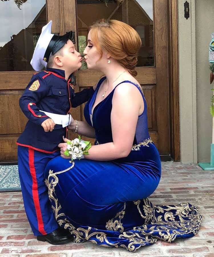 Marine's girlfriend and little brother pose like they are kissing