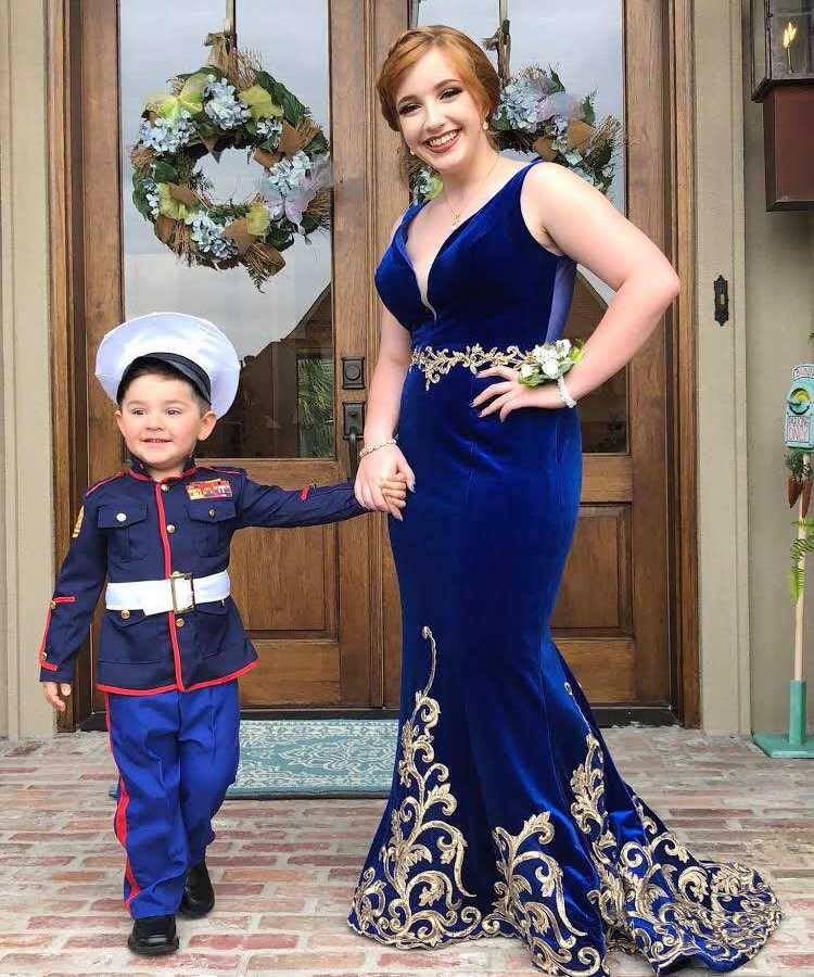 Marine's girlfriend holds his little brothers hand who is taking her to prom