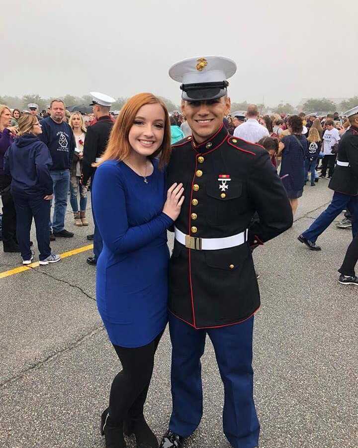 Marine smiles with arm wrapped around girlfriend