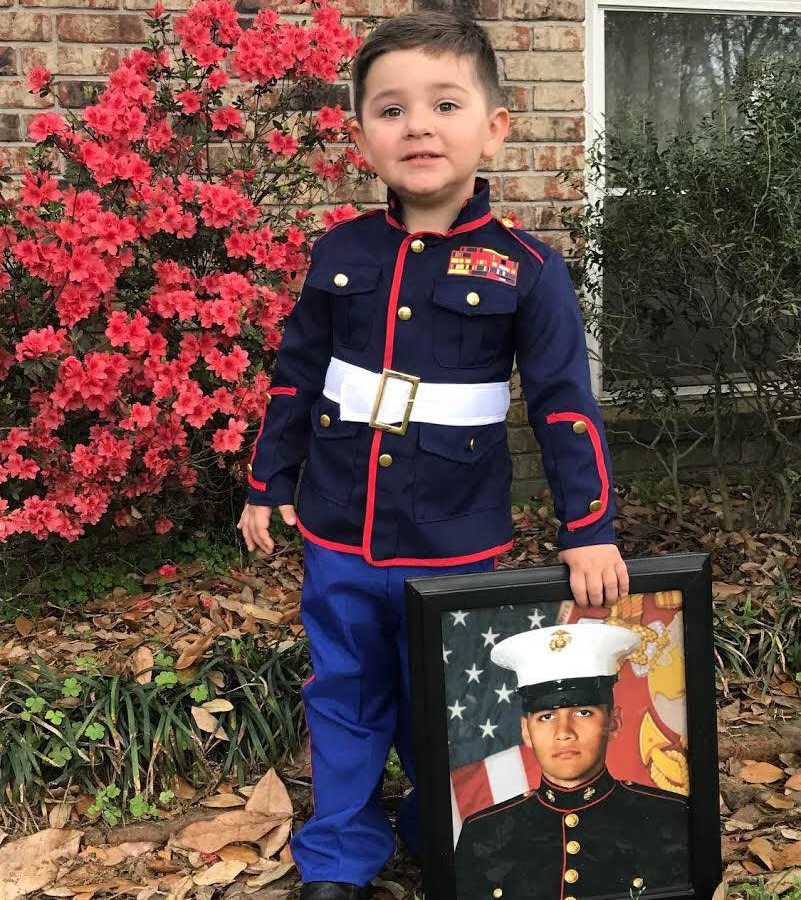 Marine's 2 year old brother wears marine uniform holding frame of older brother