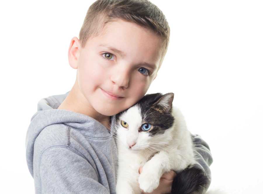 Boy who was bullied at school holds rescued cat with similar eyes