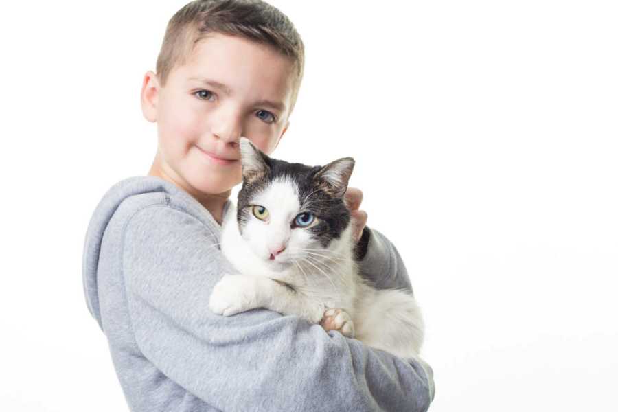 Boy who was bullied at school holds his rescue cat that makes him feel better