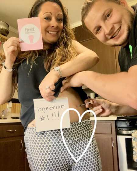 Husband smiles while injecting needle into wife's stomach for IVF