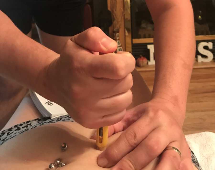 Close up of husband injecting IVF medication into wife's stomach