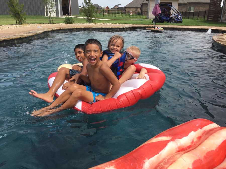 Birth son and daughter on pool floaty with adopted brothers