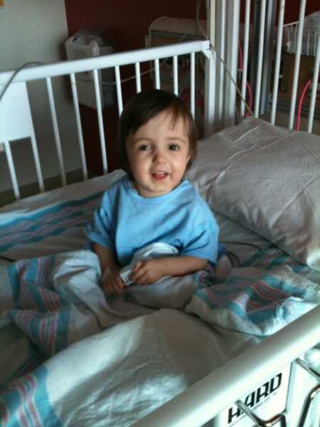 Little girl who received a kasai procedure sits up smiling in hospital bed