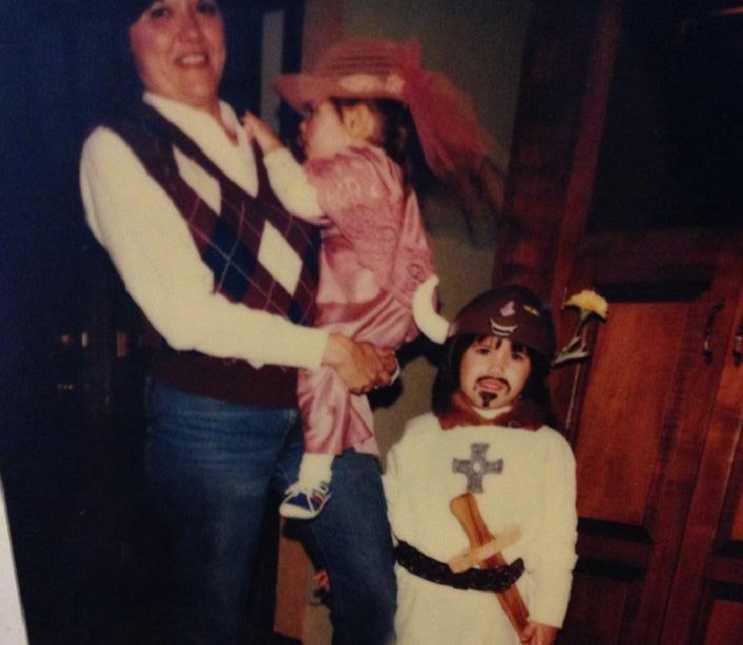 Woman with small cell cancer when she was younger holding her daughter standing next to other daughter dressed in costume