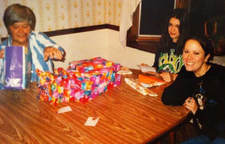 Woman with small cell cancer when she was younger at table full of presents with two granddaughters