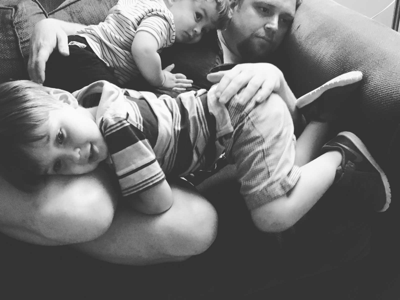 Man who needs kidney transplant curled up on couch with sons sitting on top of him