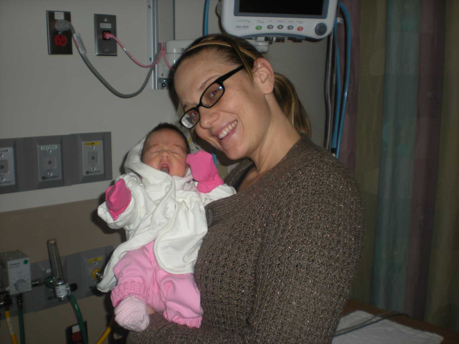 Mother smiles in hospital while holding baby daughter who has biliary atresia