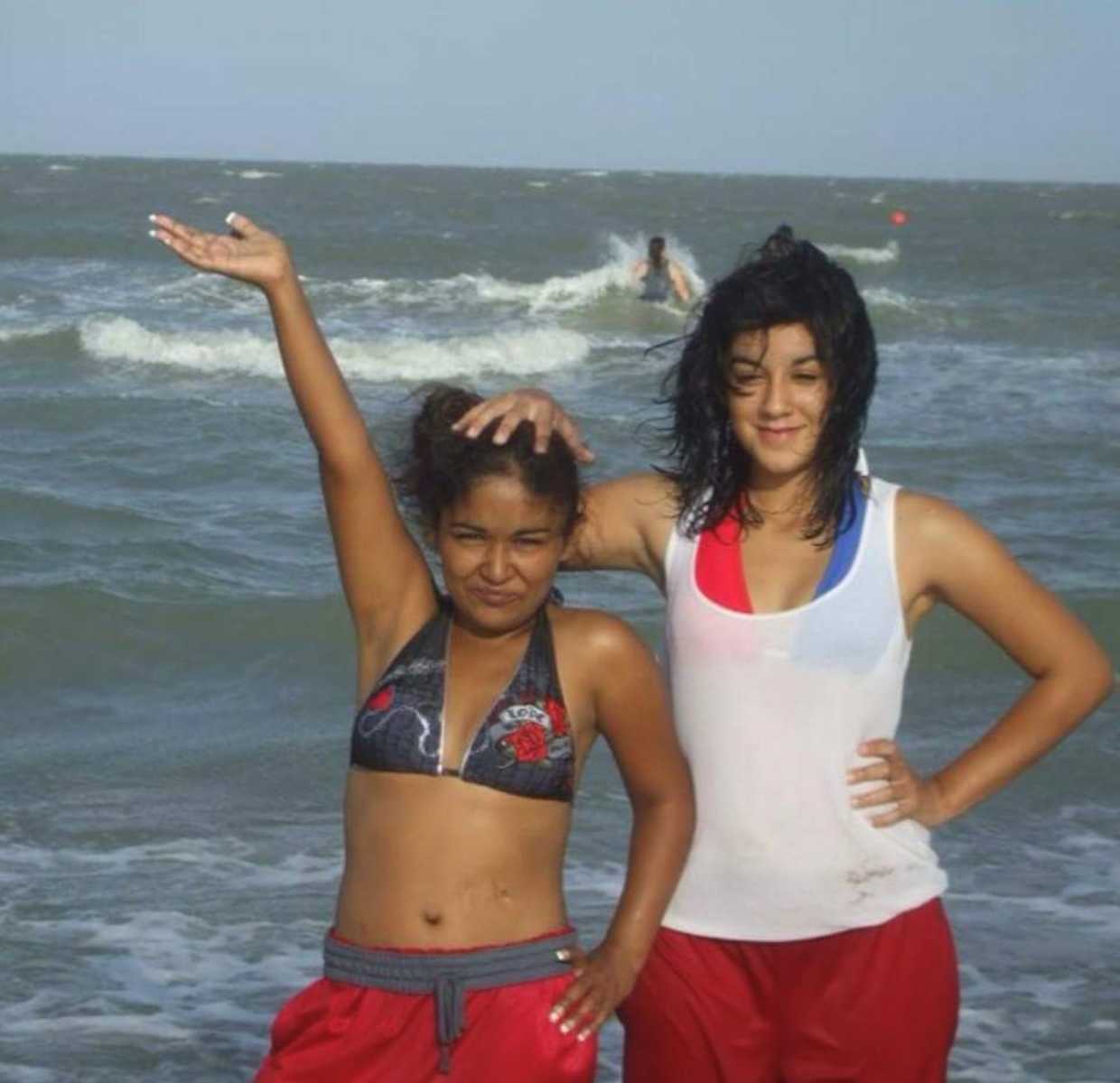 Older sister with kidney issues who would soon pass away stands with hand on little sister's head at beach