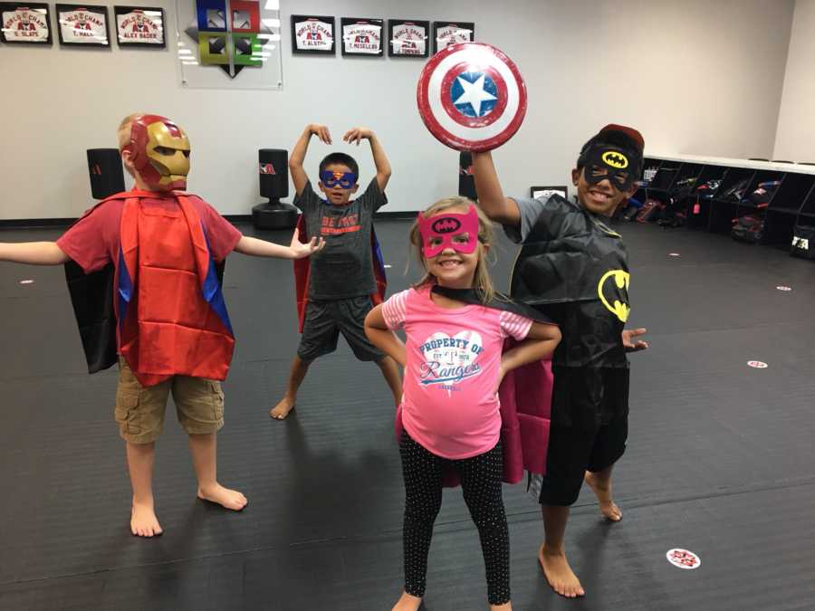 Birth son and daughter along with their two adopted brothers wearing super hero costumes