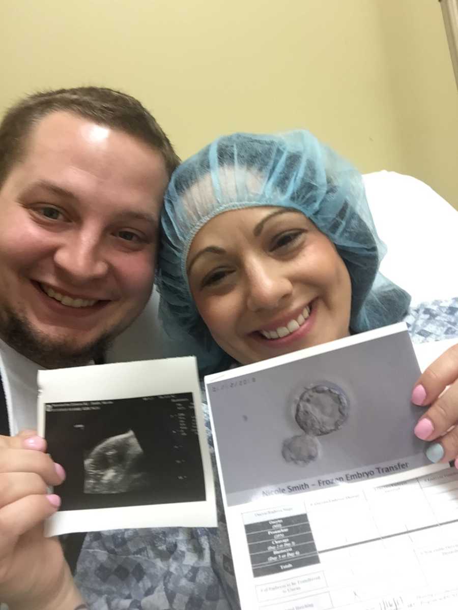Husband and wife smile in selfie while holding up ultrasound of baby conceived through IVF