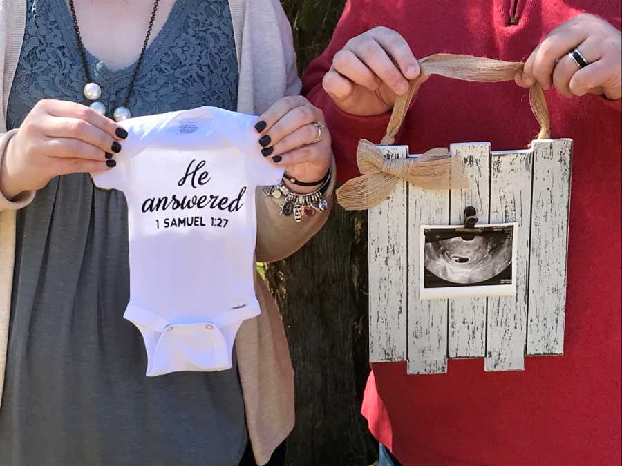 Husband holds ultrasound and wife who was infertile holds onesie