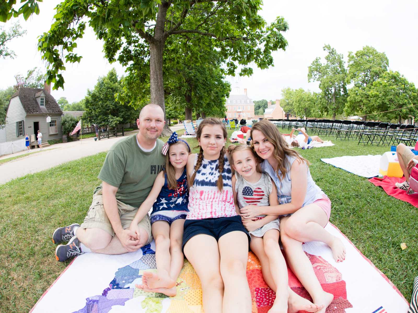 Adoptive parents sit on blanket with birth children 