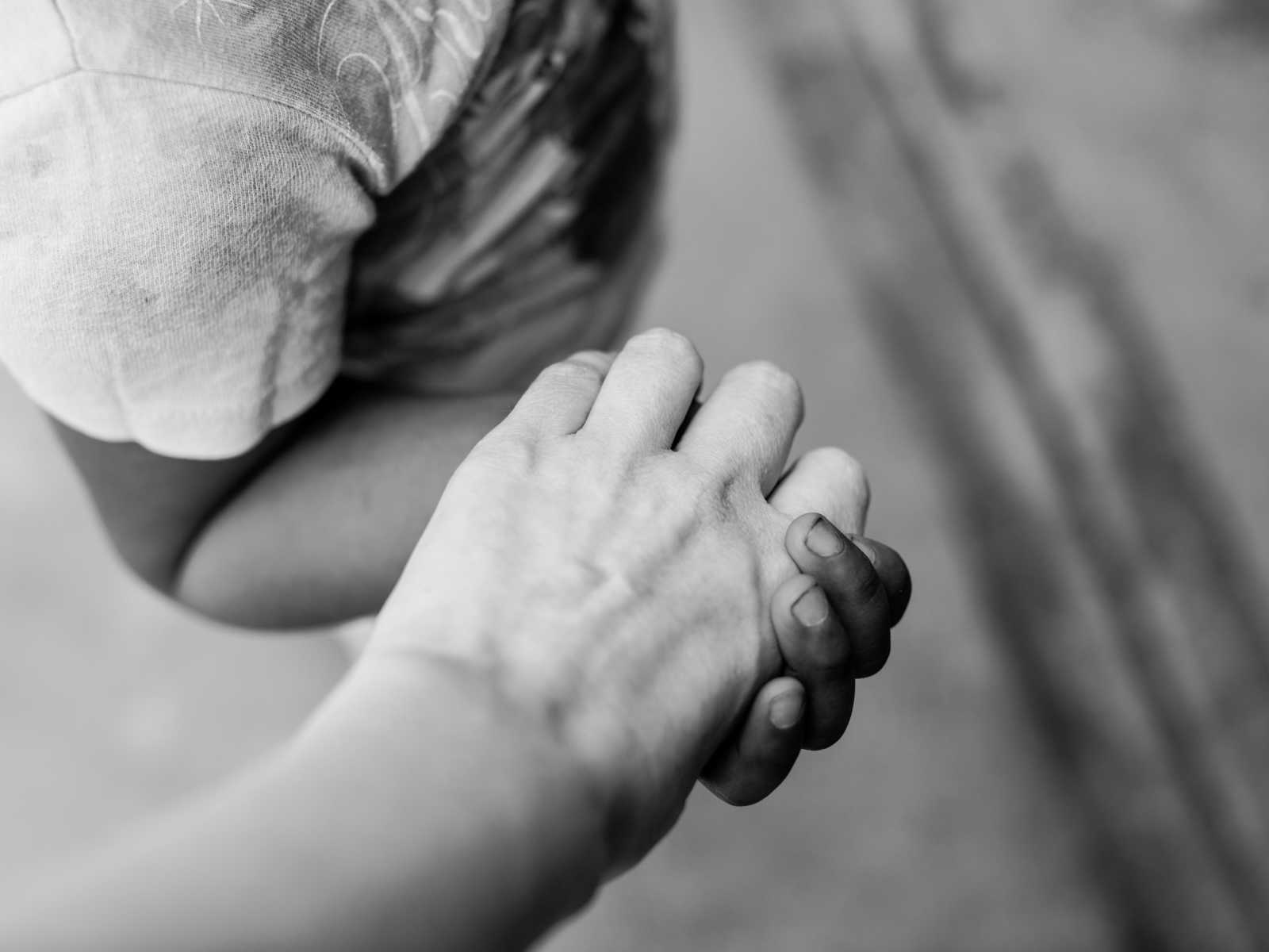 Close up of mother holding adopted daughter from Mexico's hand