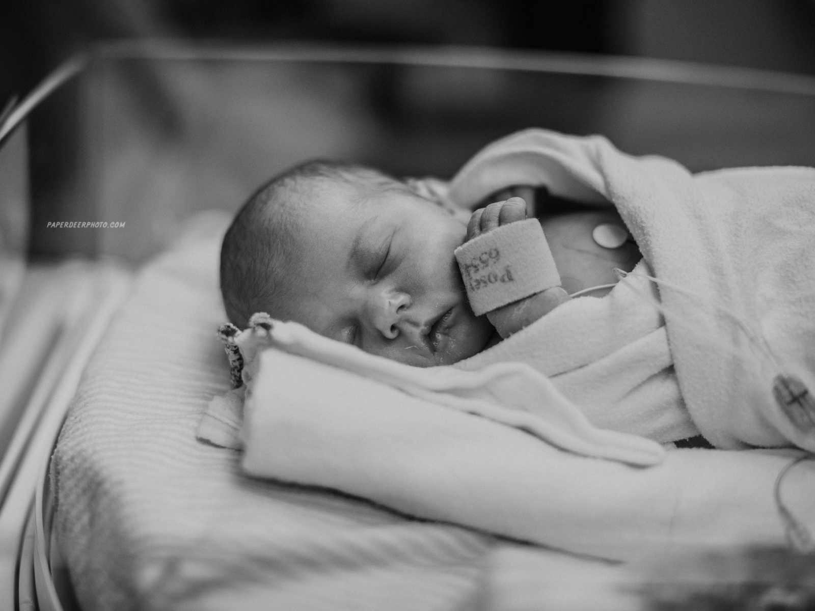 Newborn baby sleeping in hospital wrapped in blankets