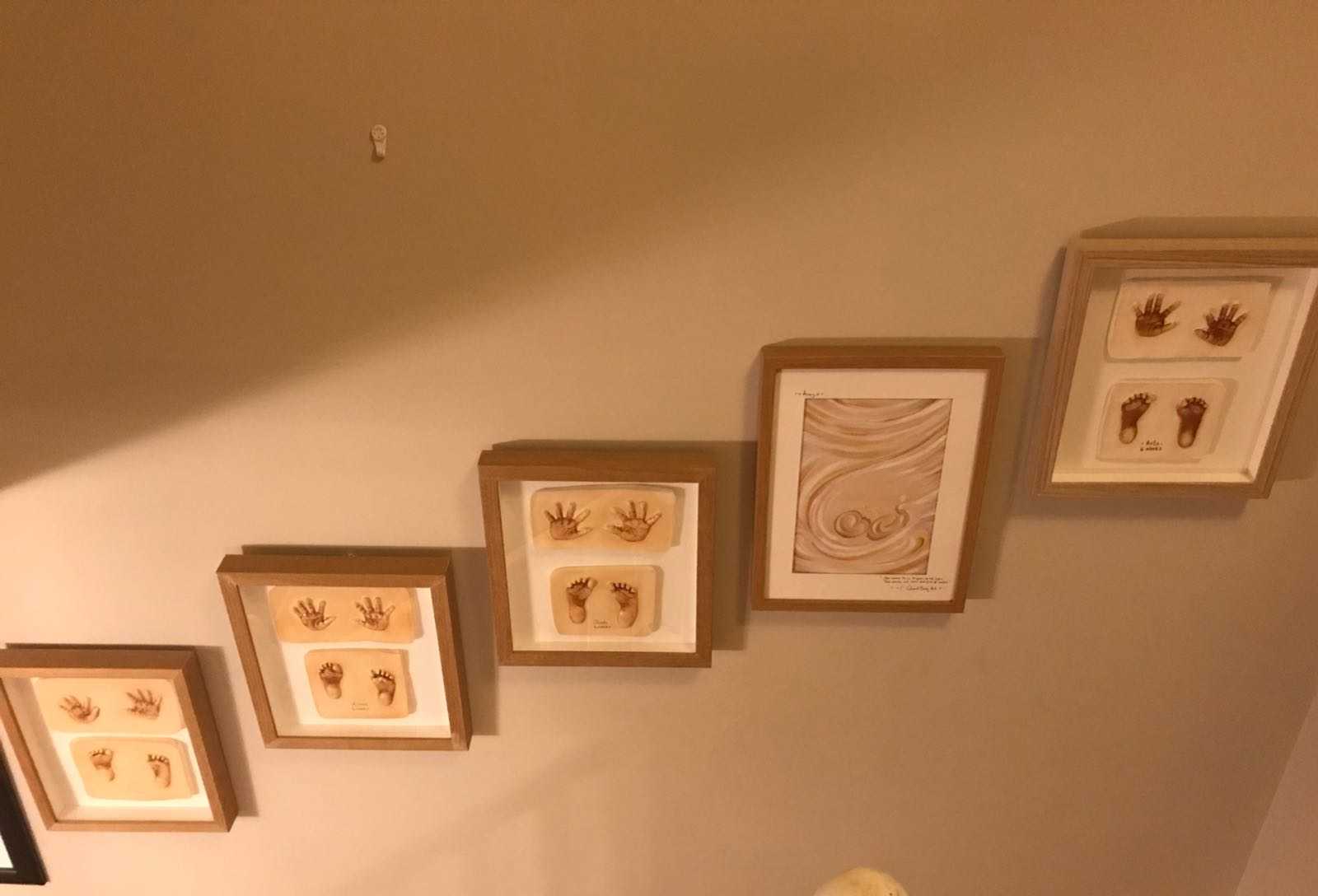 Framed ultrasound painting in hallway next to framed baby hand and foot prints