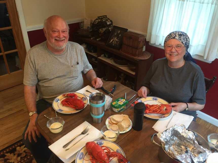 Woman with small cell cancer and husband smiling at kitchen table with lobsters on their plates