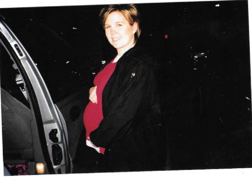 Surrogate woman smiles while holding stomach