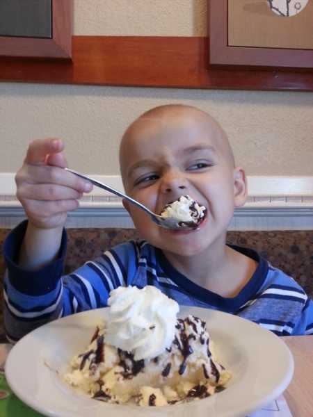Boy with leukemia taking a big big of ice cream sundae
