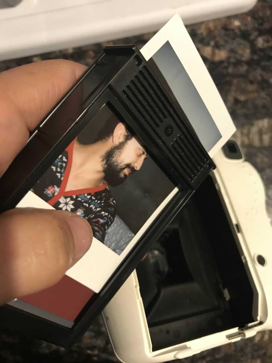 Polaroid picture of man coming out of camera