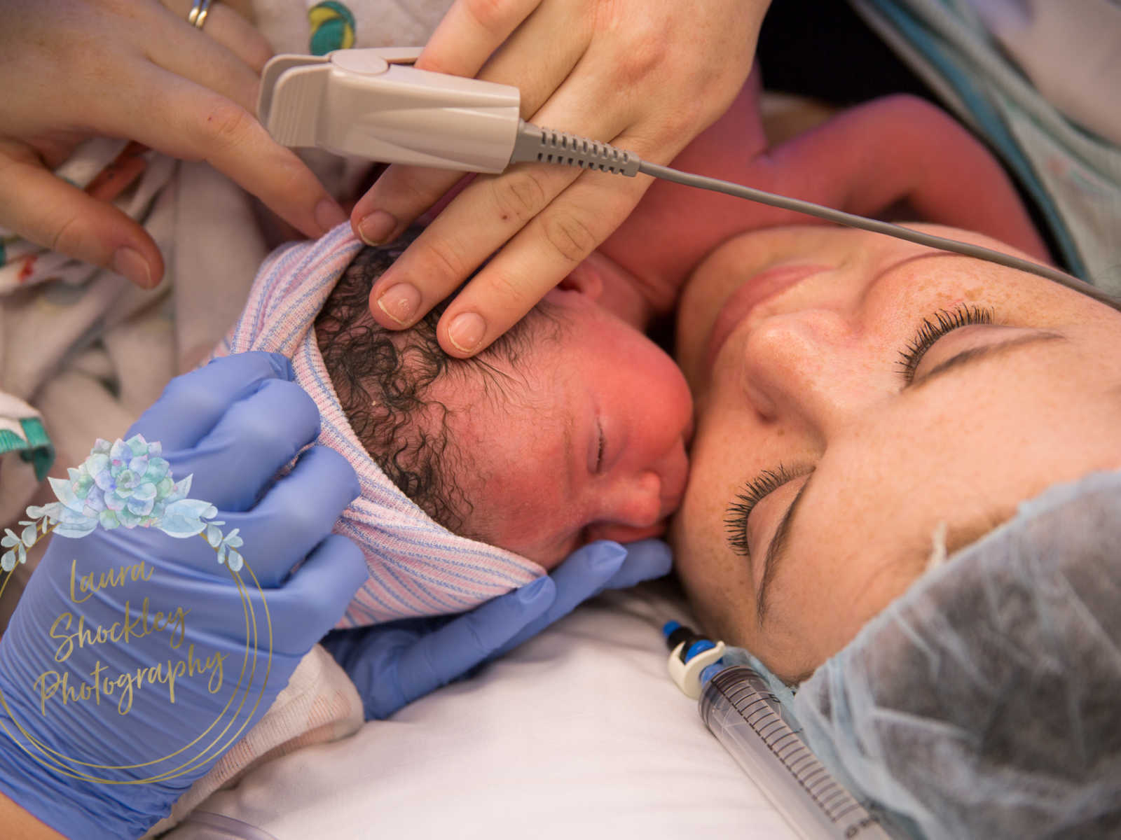 Close up of mother who was in labor for four days holding her newborns head who is snuggled to her chest