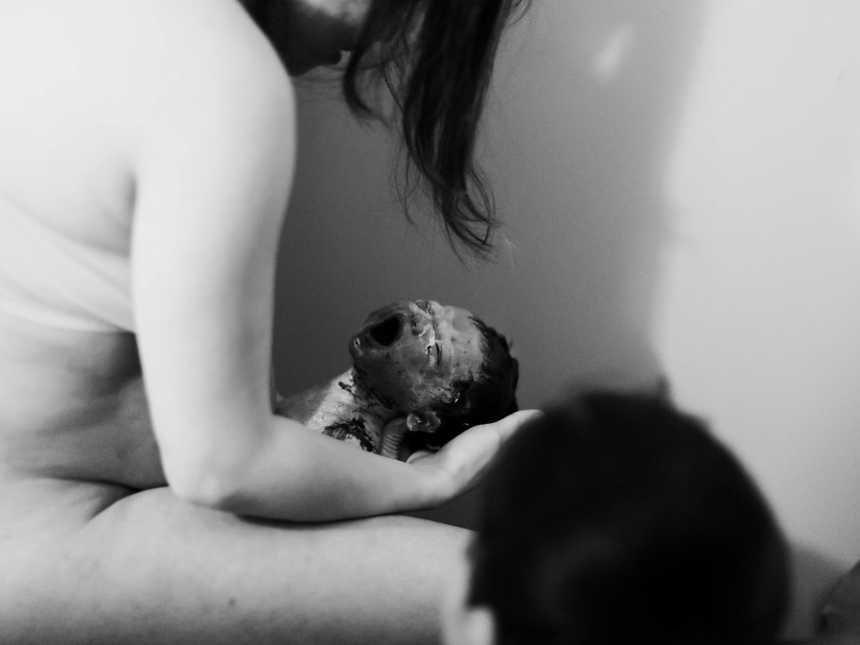 Woman who just gave birth looks down at newborn