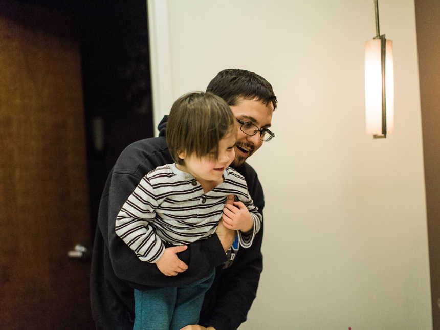 Father holds up firstborn to look at new baby sister